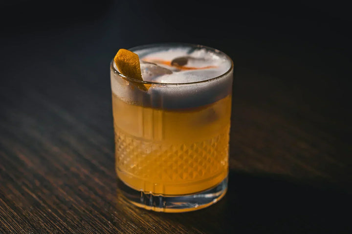 whiskey sour sitting on the counter of a dimly lit bar