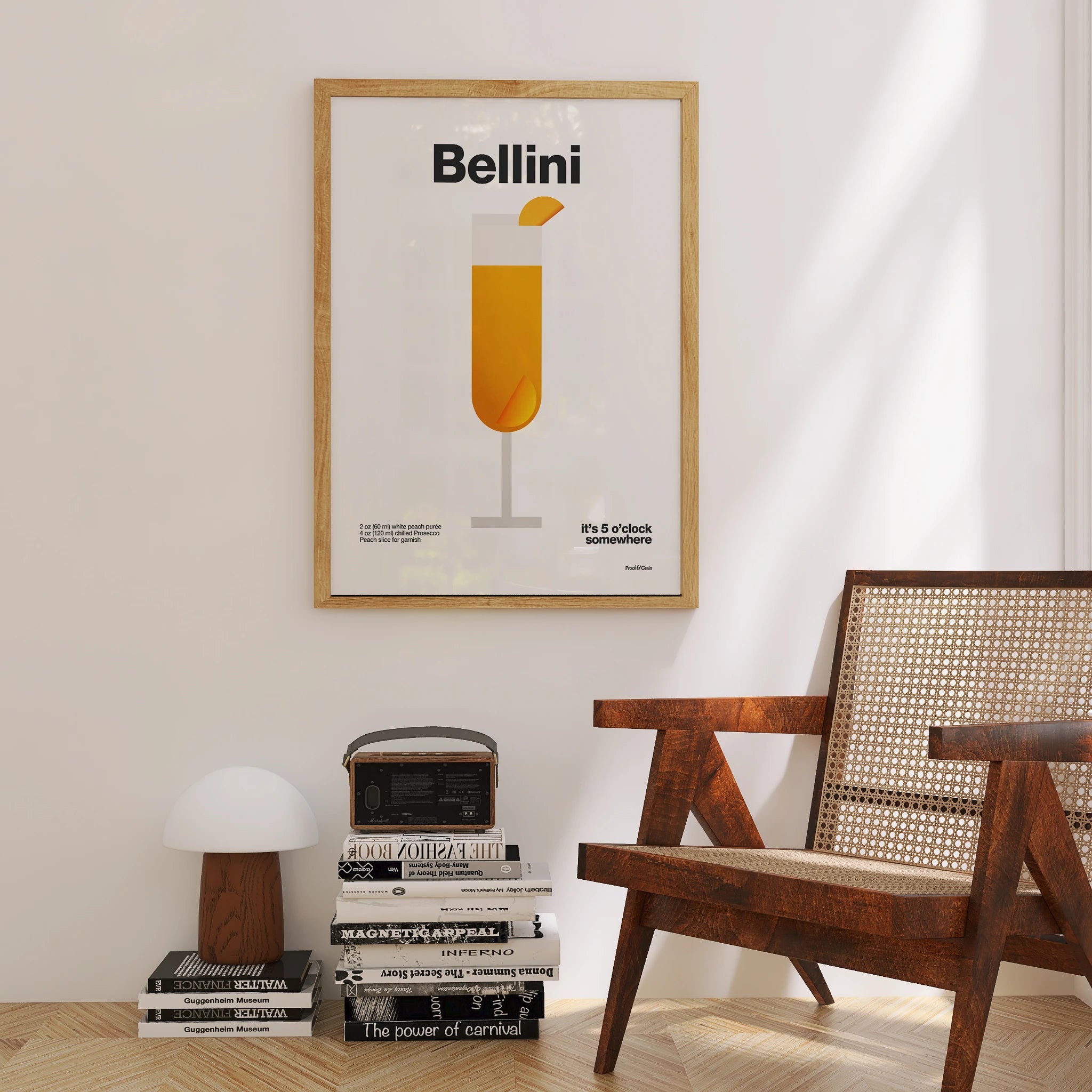 Framed Bellini poster on a wall with a wooden chair and books below.