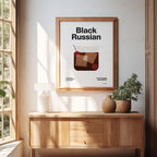 Framed poster with 'Black Russian' cocktail design on a wall in a bright room.