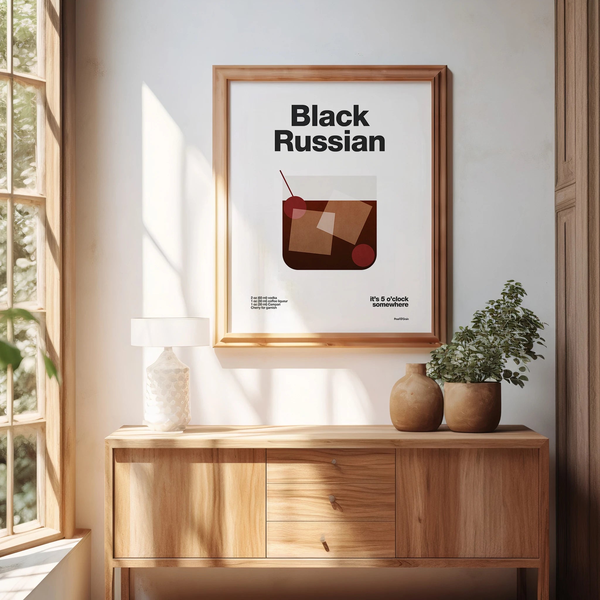 Framed poster with 'Black Russian' cocktail design on a wall in a bright room.