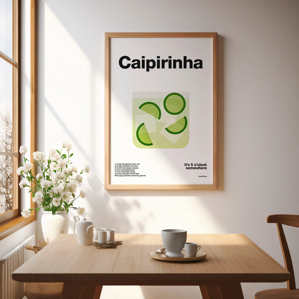 Framed poster with 'Caipirinha' design in a room with a table and flowers.