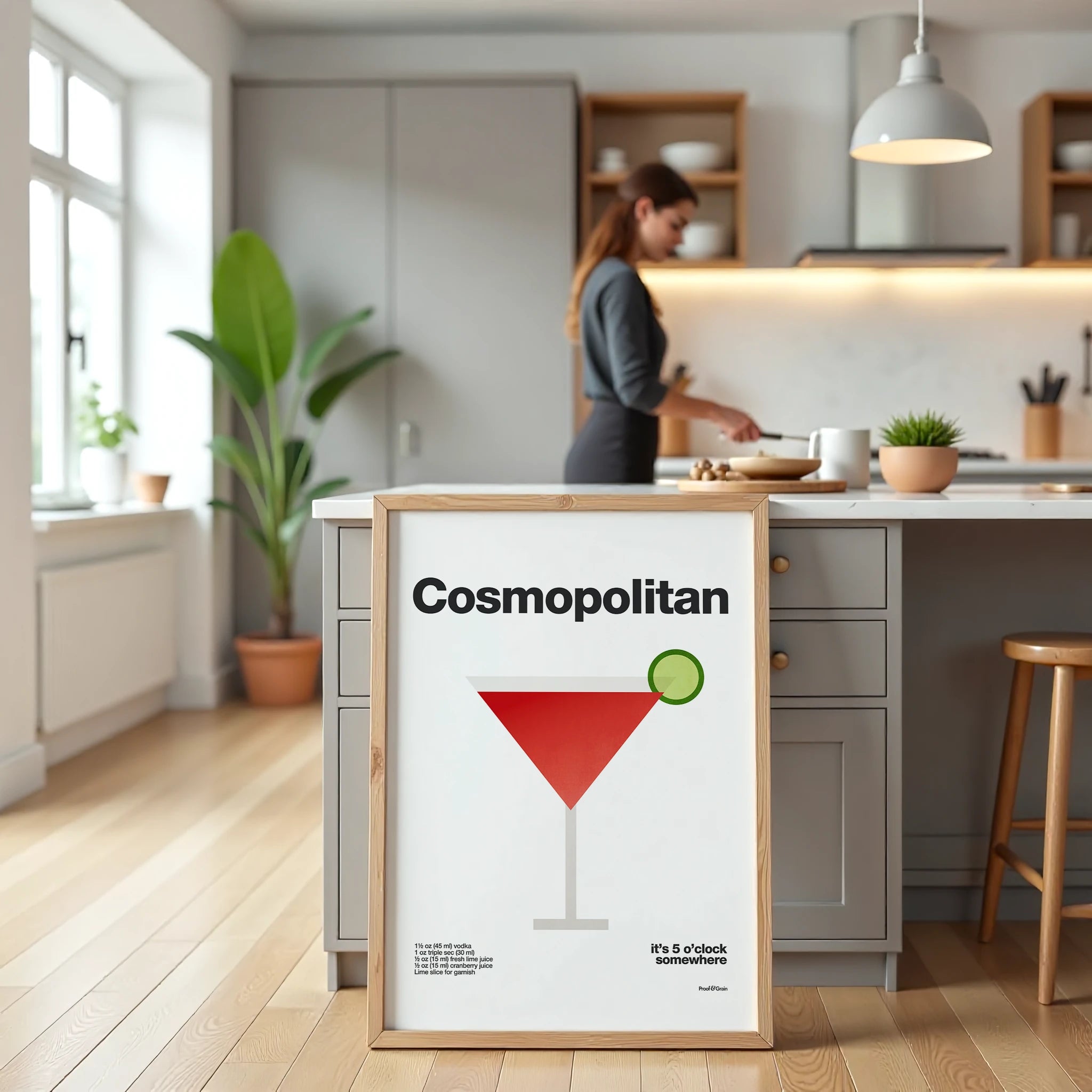 Modern kitchen with a framed 'Cosmopolitan' cocktail poster on a kitchen island.