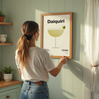 Woman hanging a framed picture of a daiquiri on a wall