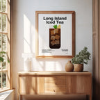 Framed poster of a Long Island Iced Tea on a wall above a wooden cabinet with plants.