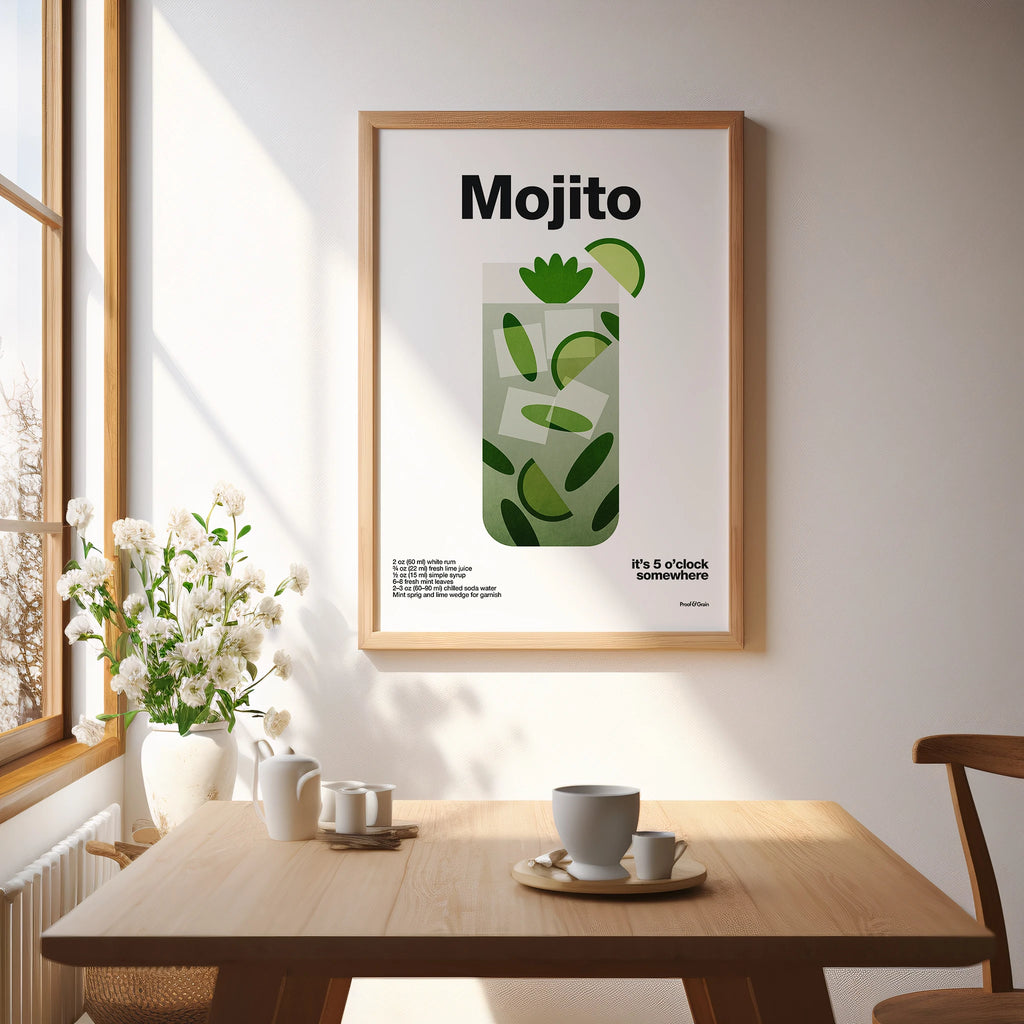 Framed Mojito poster on a wall above a wooden table with decor items.