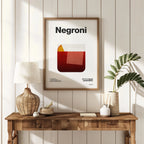 Framed 'Negroni' poster on a wall above a wooden console table with decor items.