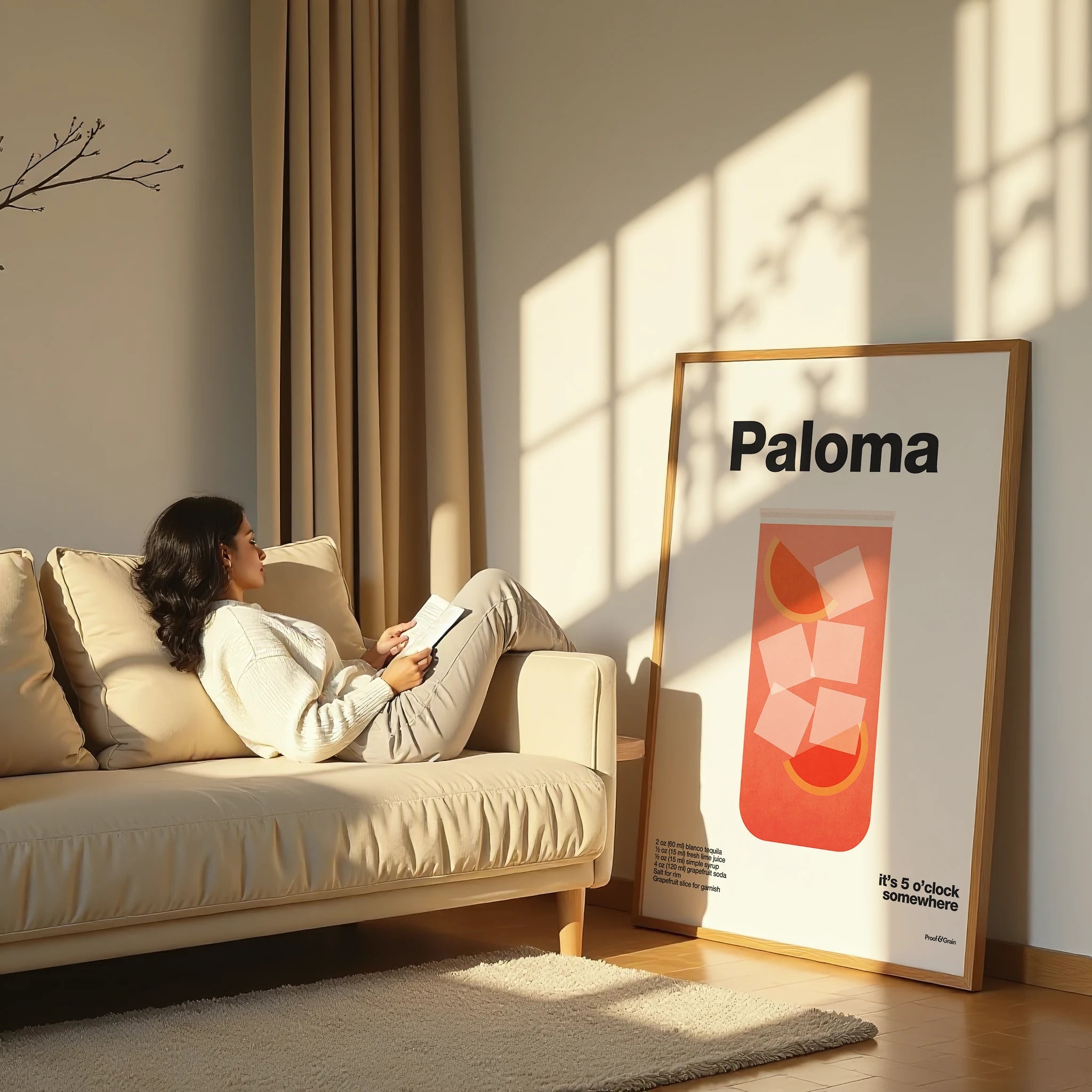 Woman reading a book on a beige sofa in a sunlit room with a 'Paloma' poster on the wall.