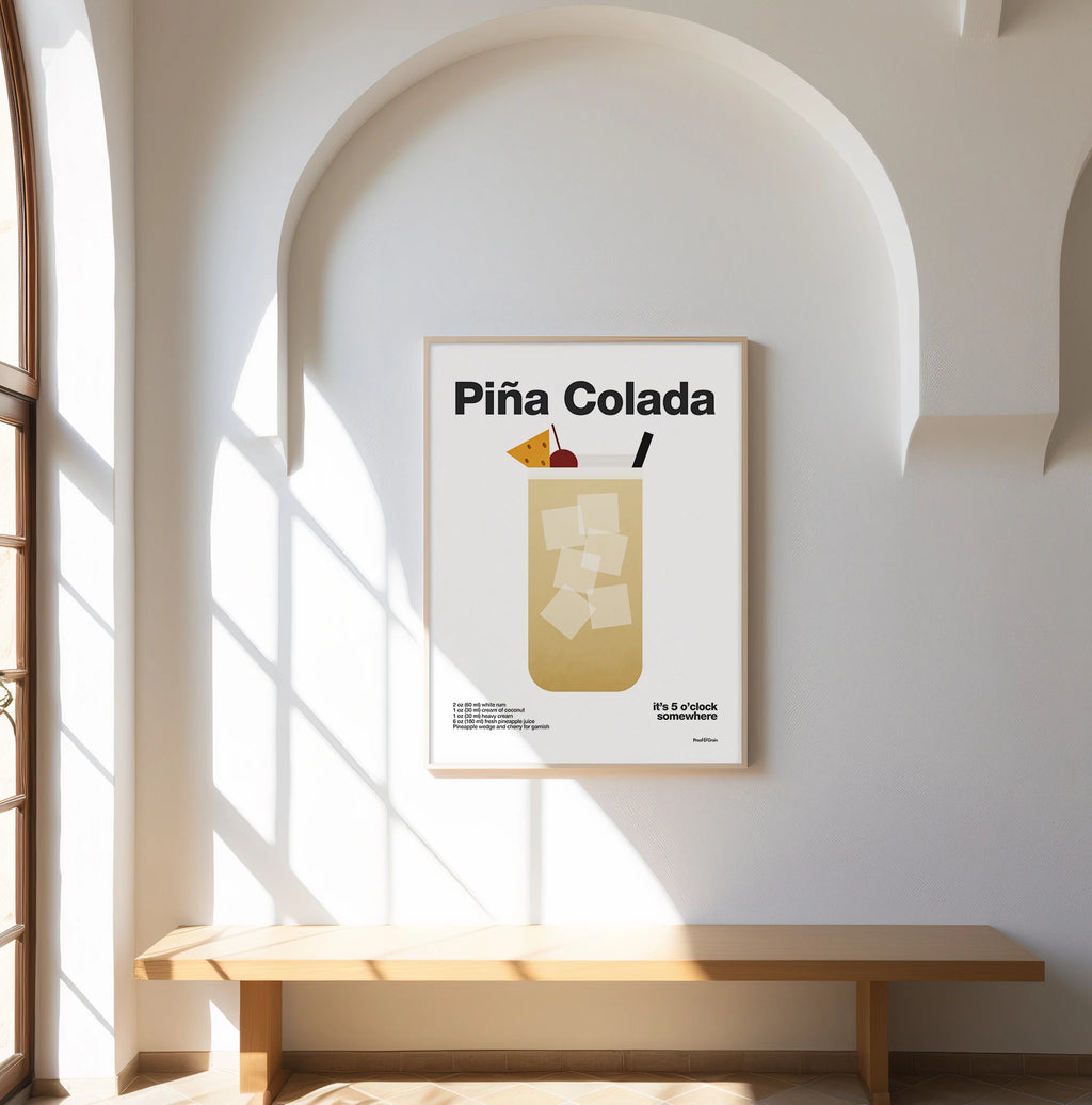 Framed Piá Colada poster on a wall with sunlight streaming through a window.